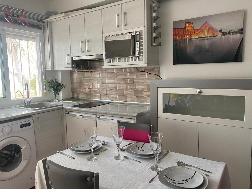 a kitchen with a table with plates and wine glasses at ESTUDIO EN SANJOSE A 50 M DE LA PLAYA in San José