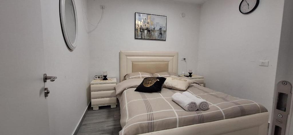 a white bedroom with two beds and a mirror at RutSuite in Afula