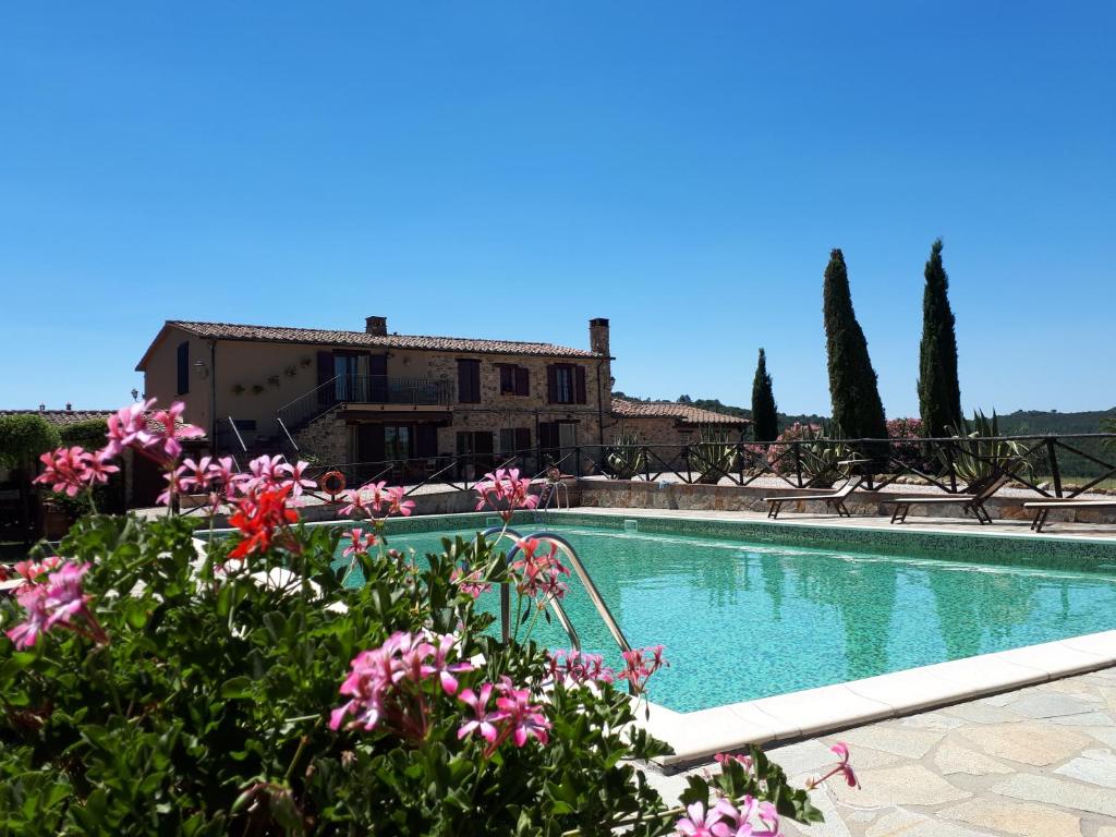 a swimming pool with pink flowers in front of a building at Agriturismo Podere San Lorenzo 1866 in Massa Marittima
