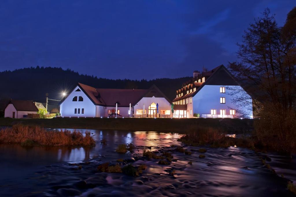 a house lit up at night next to a river at Hotel Vír in Vír