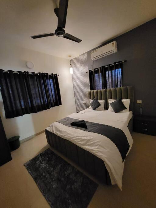 1 dormitorio con 1 cama grande y ventilador de techo en THE PERFECT STAYS: SUPREME BLISS VILLA en Lonavala