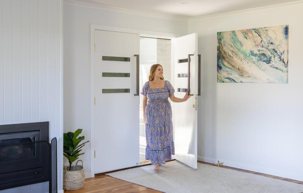 Una donna con un vestito blu sta aprendo una porta di Owl+Oak a Castlemaine