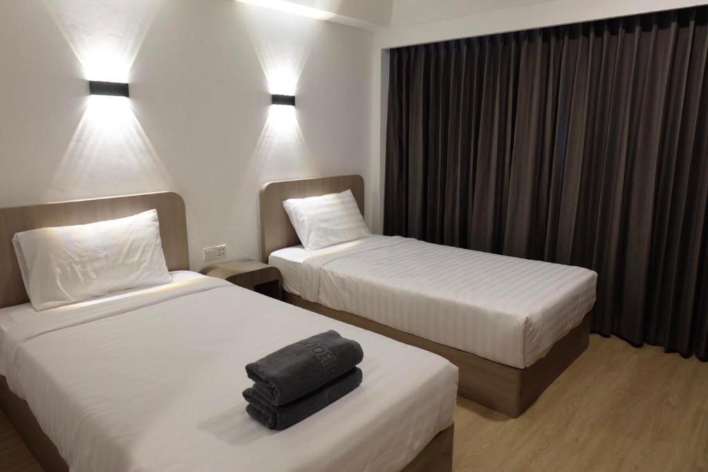 a hotel room with two beds and a suitcase on the bed at U-Thong Hotel in Phitsanulok