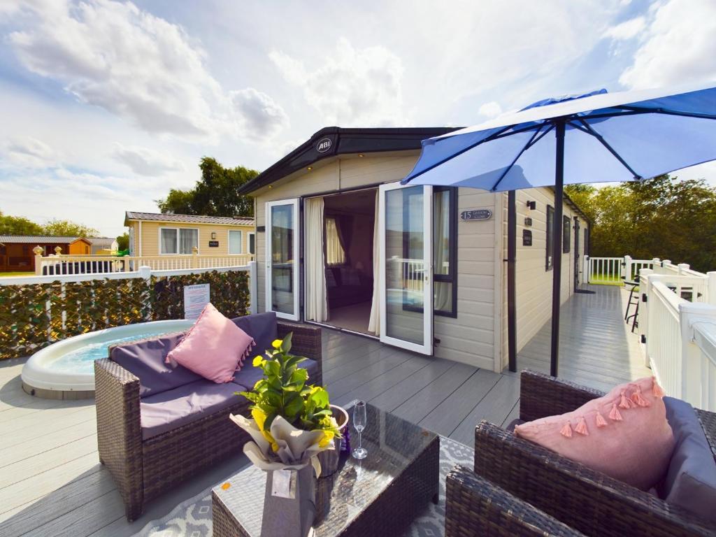 een terras met tuinmeubilair en een parasol bij Tattershall Lakes Mini Breaks - Gibson Close in Lincoln