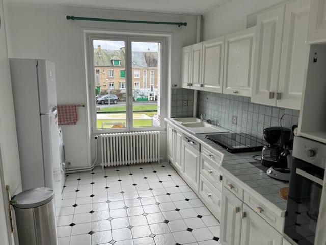 eine Küche mit weißen Schränken und Fliesenboden in der Unterkunft Hubert in Carignan