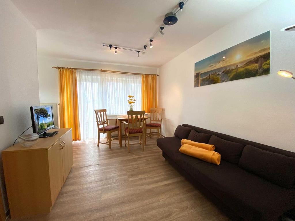uma sala de estar com um sofá e uma mesa de jantar em Süderhaus Hiddensee App 4 em Neuendorf