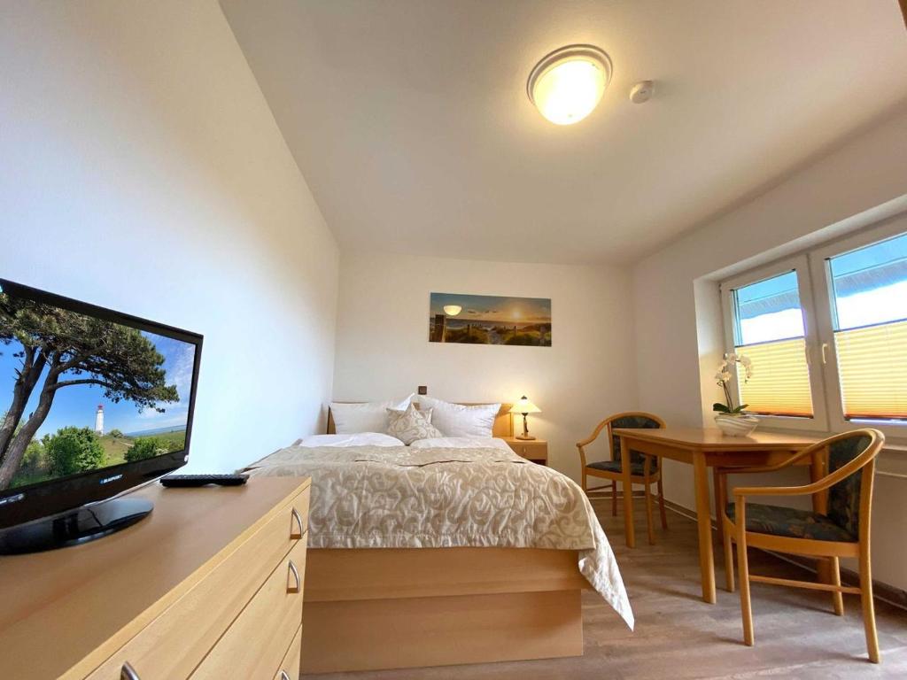 a bedroom with a bed and a desk and a television at Süderhaus Hiddensee App 3 in Neuendorf