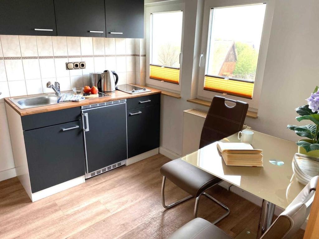 - une cuisine avec un évier et une table dans une chambre dans l'établissement Süderhaus Hiddensee App 8, à Neuendorf