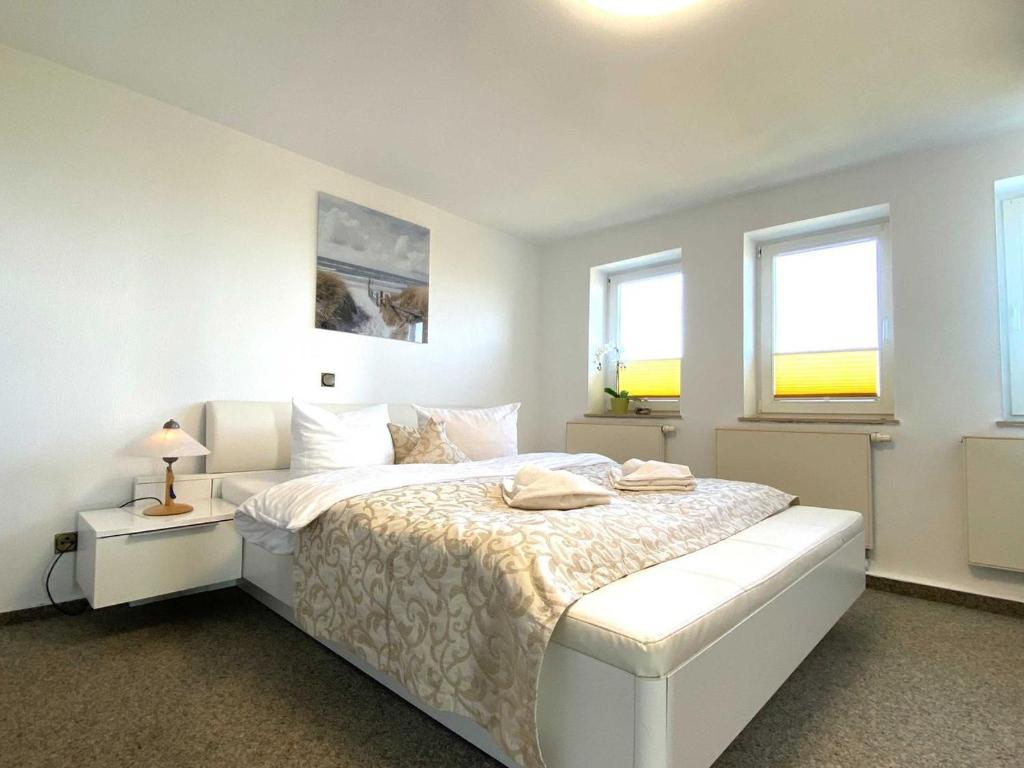 1 dormitorio blanco con 1 cama blanca y 2 ventanas en Süderhaus Hiddensee App 14, en Neuendorf