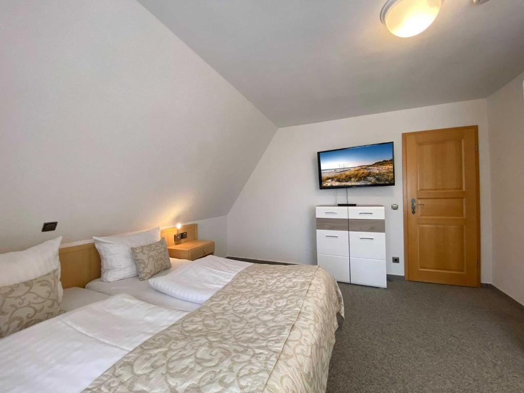 a bedroom with a bed and a flat screen tv at Süderhaus Hiddensee App 6 in Neuendorf