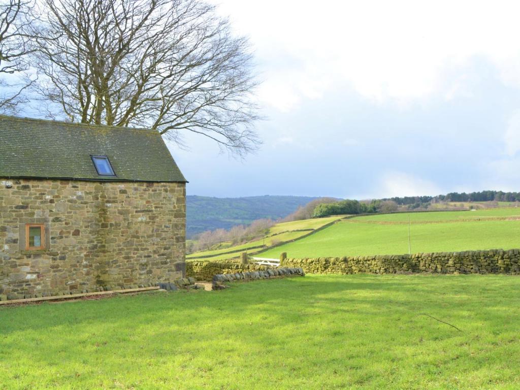 a stone building in a field next to a stone wall at 2 Bed in Tansley 78219 in Tansley