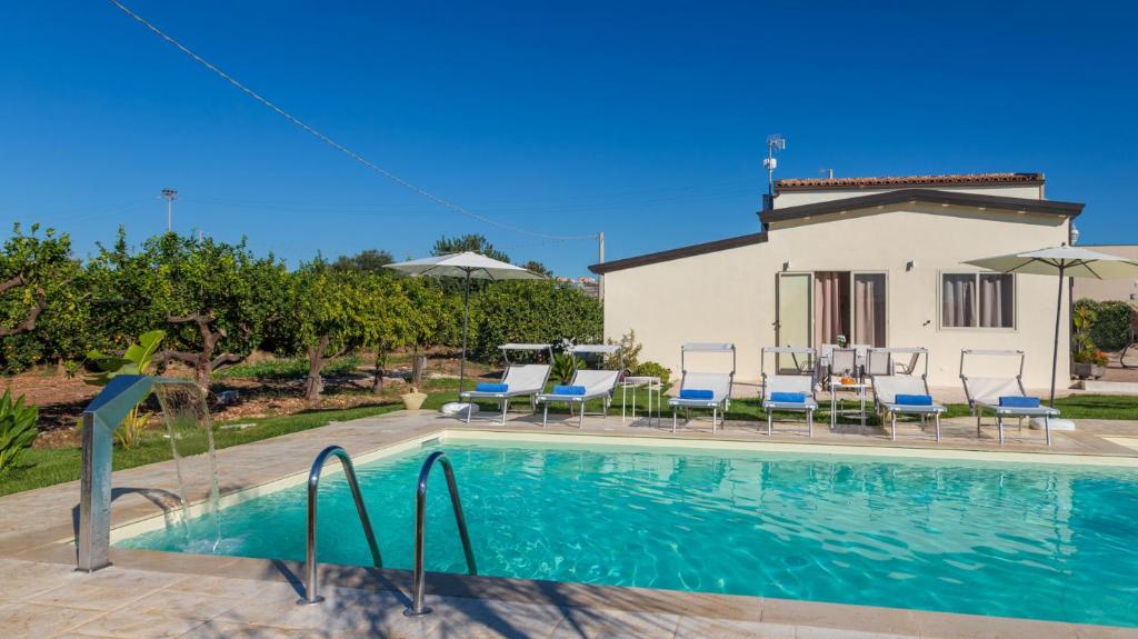 a swimming pool with chairs and a house at PROFUMO DI ZAGARA 6&2 Emma Villas in Ispica