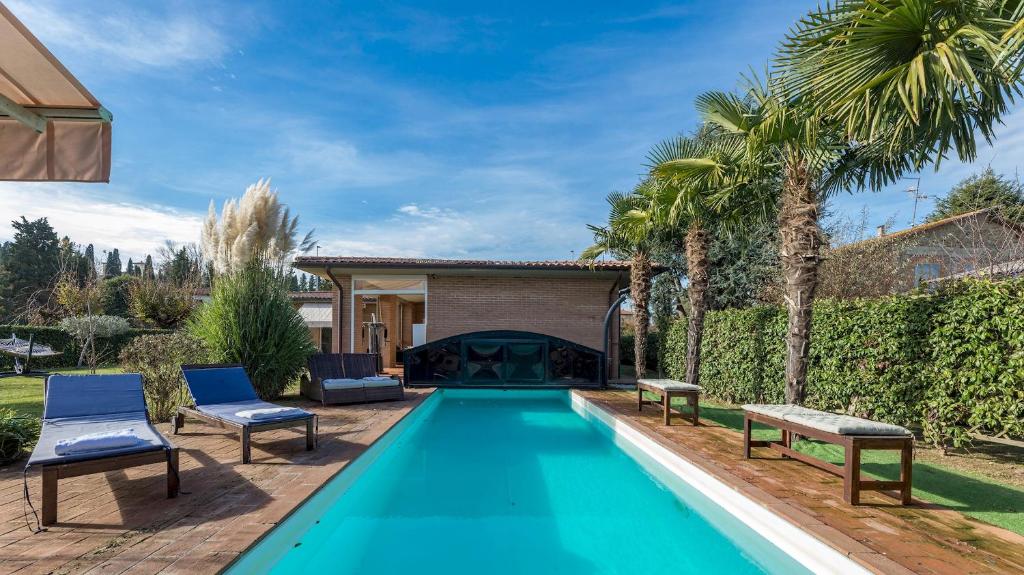 - une piscine dans une cour avec 2 chaises bleues et une maison dans l'établissement VILLA VIVI' 8, Emma Villas, à Monte San Savino