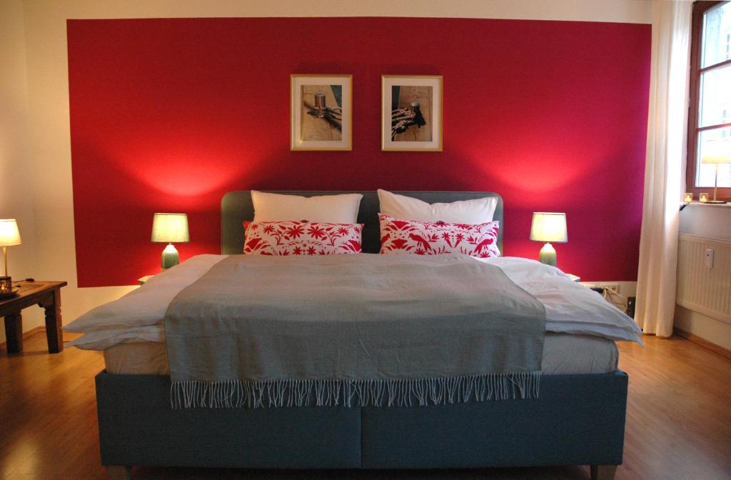 a bedroom with a red wall and a bed with pillows at Suite - Mein Ankerplatz in Stralsund