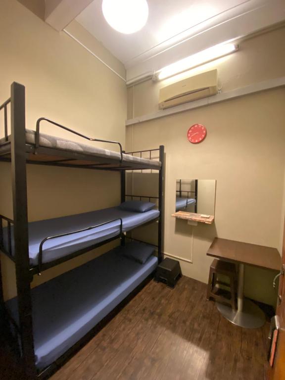 a room with bunk beds and a clock on the wall at Backpacker Cozy Corner Guesthouse in Singapore