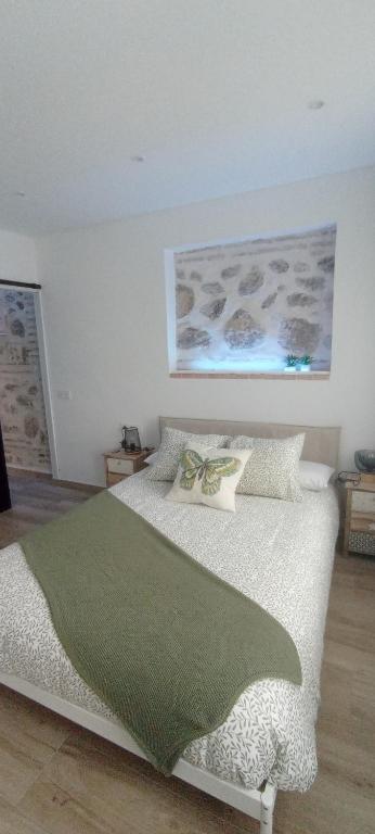 a bedroom with a bed with a green blanket on it at El susurro del tajo La ermita in Toledo