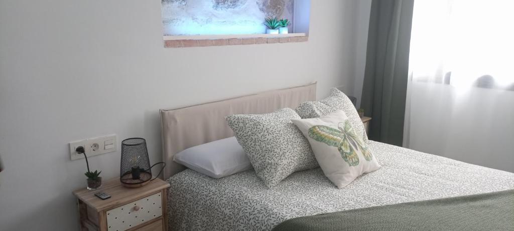 um quarto com uma cama com almofadas e uma janela em El susurro del tajo La ermita em Toledo