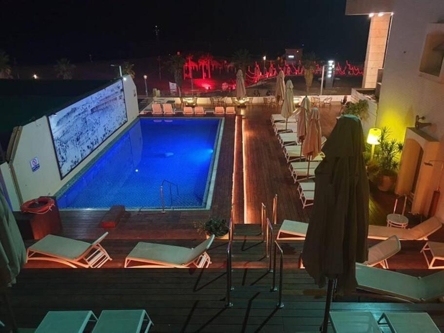 - Piscina con sillas y TV en un edificio en The Blue Lagoon With Pool By Nimizz, en Tel Aviv