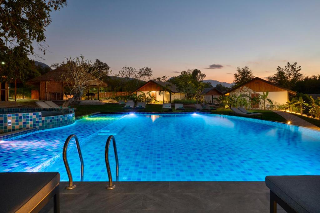 a large swimming pool at night with lights at The Namkhan in Luang Prabang