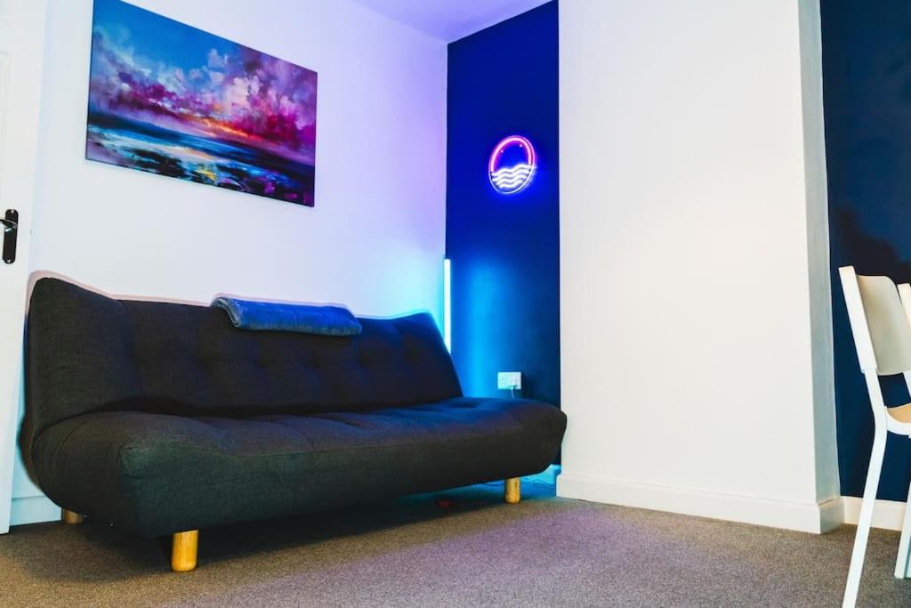 a couch in a room with a blue wall at Spacious 2BD Maisonette with Lush Loft in Newquay in Newquay