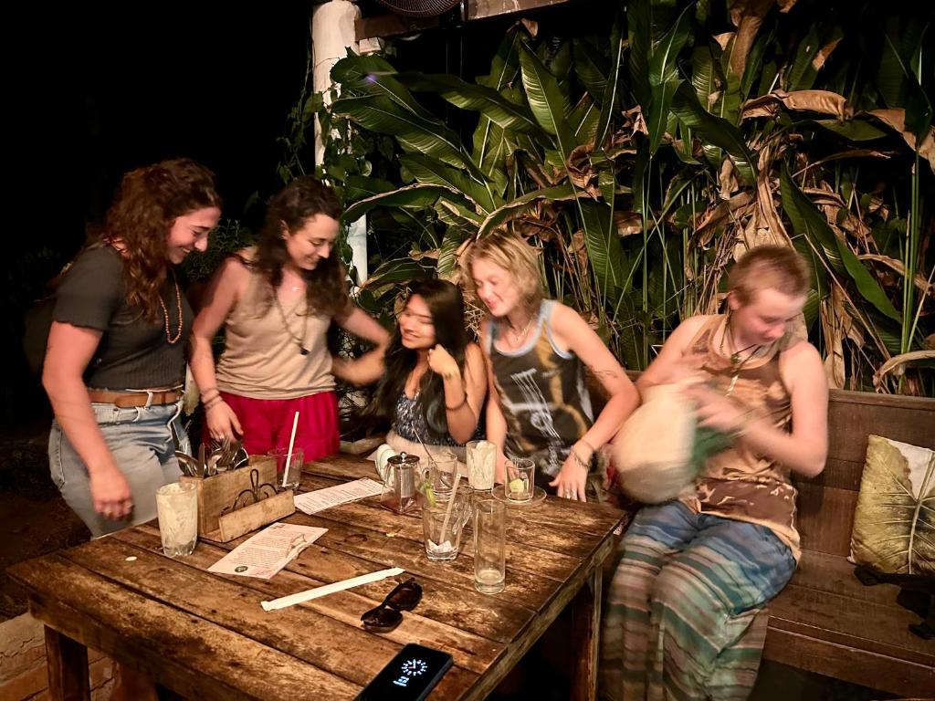 um grupo de mulheres em pé em torno de uma mesa de madeira em House Of Surf Hostel for Women em Varkala