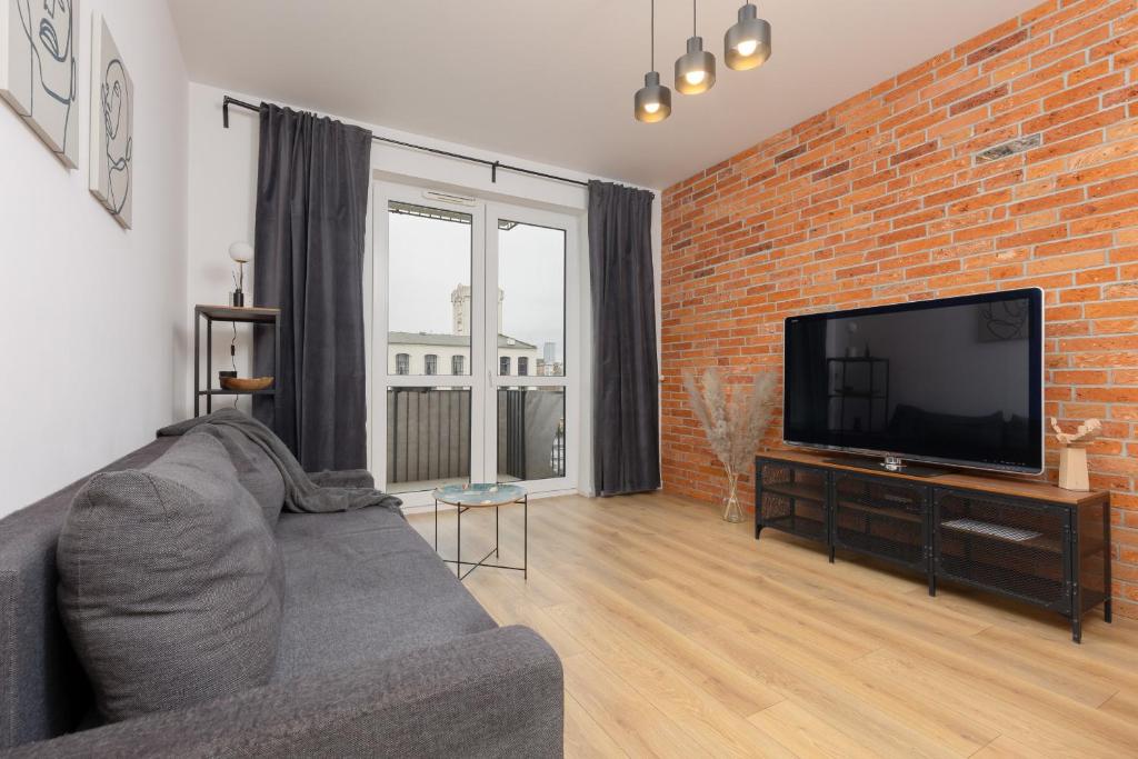 a living room with a couch and a brick wall at Minimalist Apartment in Łódź With Parking Near Łódź Kaliska by Renters in Łódź