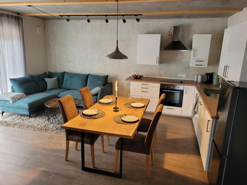 Il dispose d'une cuisine et d'un salon avec une table et des chaises en bois. dans l'établissement Wohnung unterm Burghalder - Direkt am Waldrand, à Hauenstein