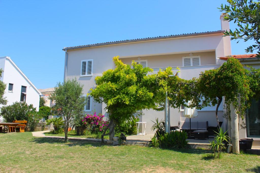 a white house with trees in front of it at Family apartments Jimmy - city center in Pag