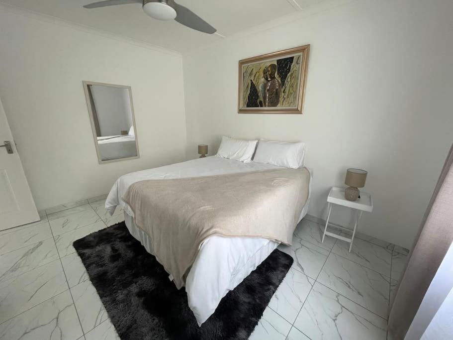 a white bedroom with a large bed and a mirror at Luxury 1 Bdr Garden Cottage in Windhoek