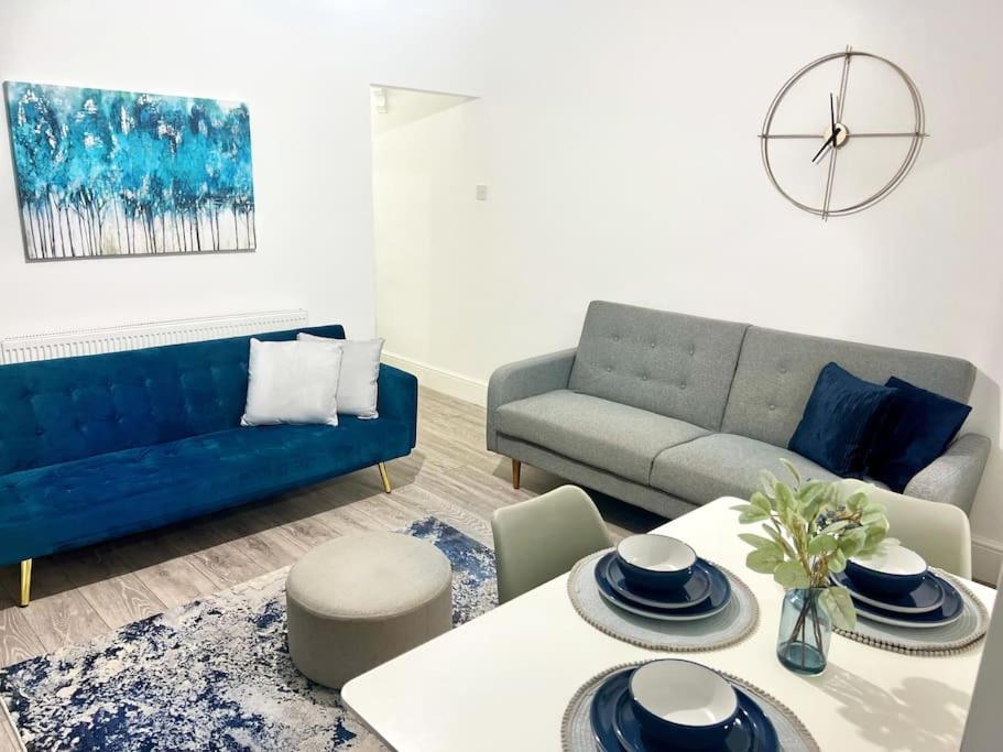 uma sala de estar com um sofá azul e uma mesa em 4BR House for Contractors em New Bilton