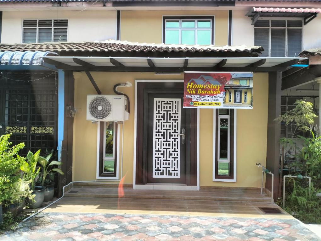 a building with a door with a sign on it at Nik Homestay in Tanah Merah