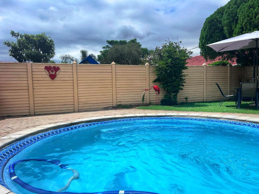 a swimming pool in a yard with a wooden fence at BUTRIN GUEST HOUSE in Welkom
