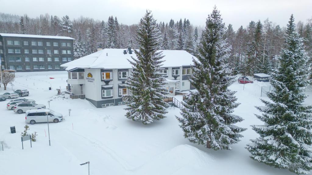 kompleks apartamentów z pokrytymi śniegiem drzewami i budynek w obiekcie Hotel Aateli Lakeside w mieście Vuokatti