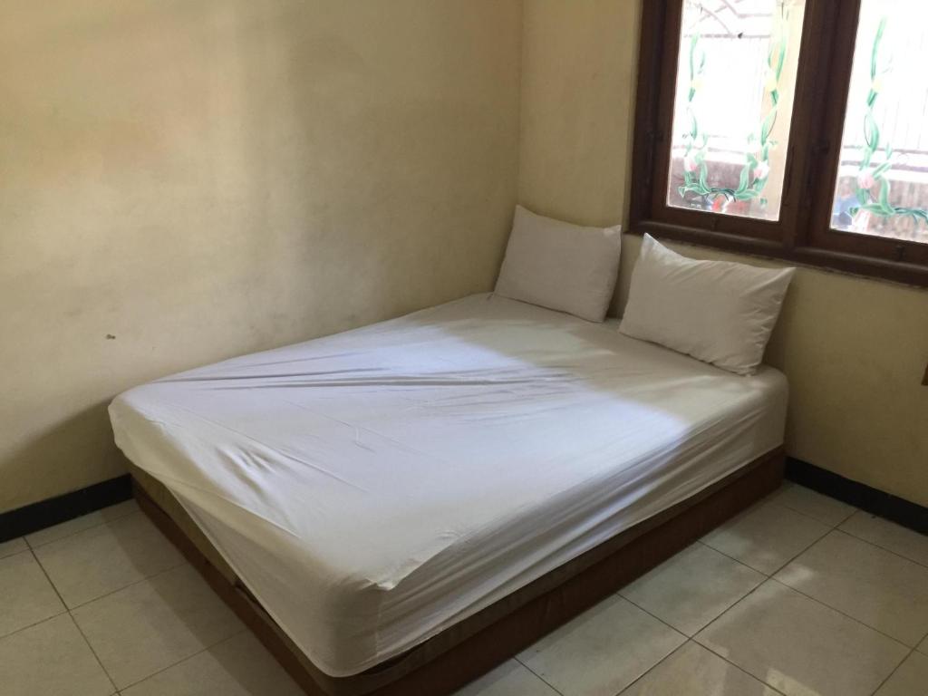 SPOT ON 93531 Homestay Puri Indah Syariah في Betro: سرير بشرشف ووسائد بيضاء في الغرفة