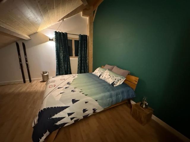 a bedroom with a bed and a green wall at LES ANTHOCYANES CHAMBRE MONTAGNE in Champagny