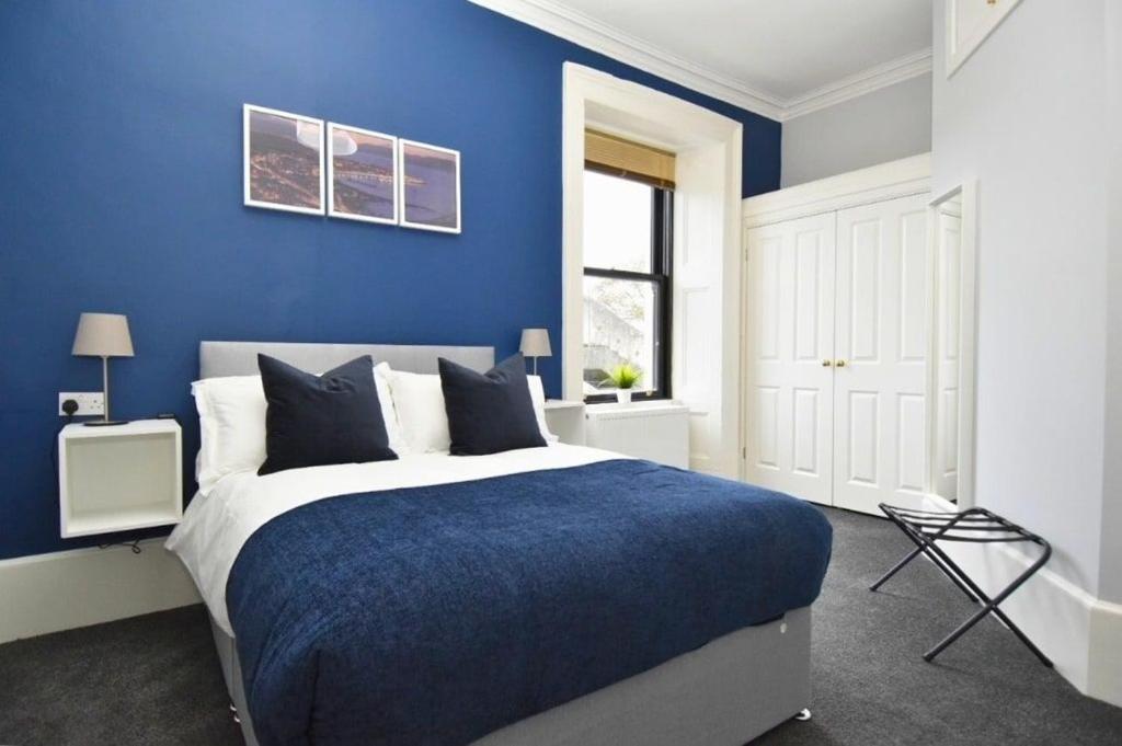 a blue bedroom with a bed with a blue wall at Exclusive Use in Gourock