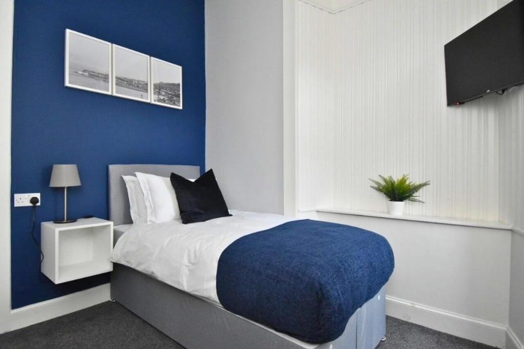 Schlafzimmer mit einem Bett mit blauer Wand in der Unterkunft The Cove in Gourock