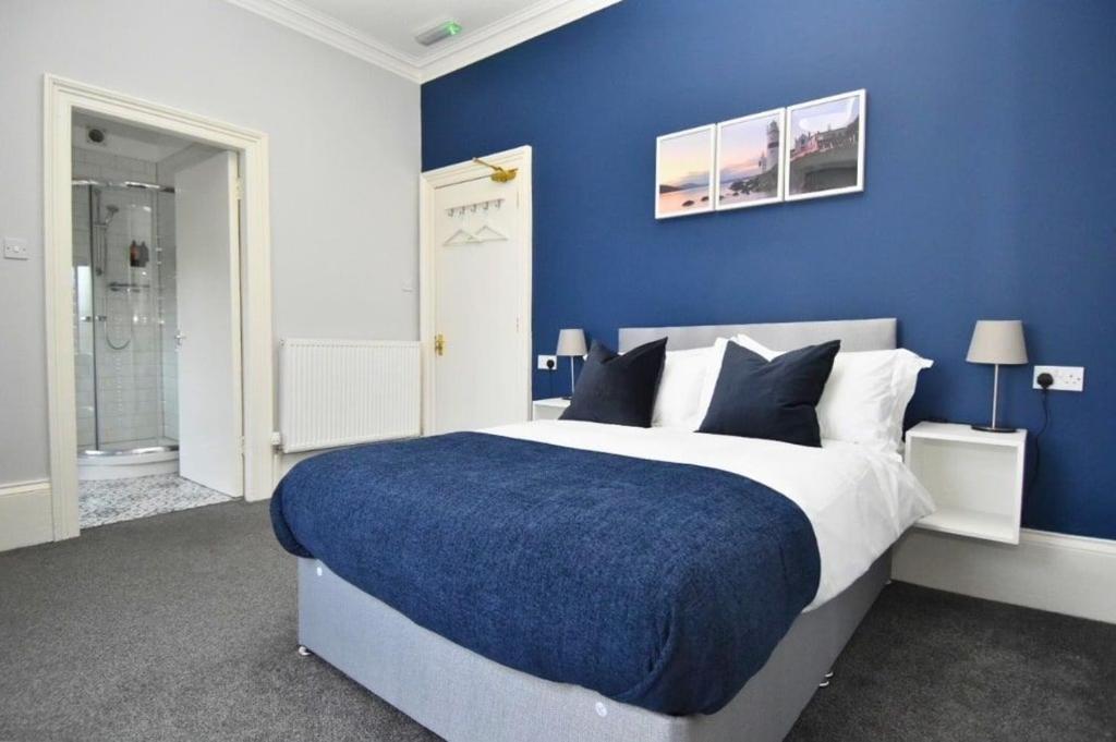a blue bedroom with a bed with a blue wall at The Cloch in Gourock