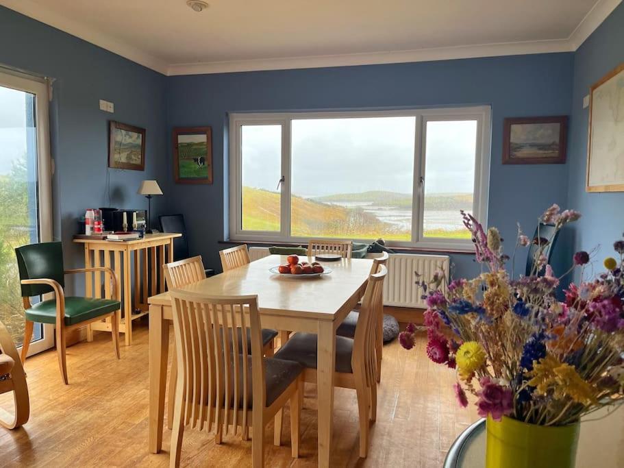 een eetkamer met een tafel en stoelen en een raam bij Sandhill, in Mulranny