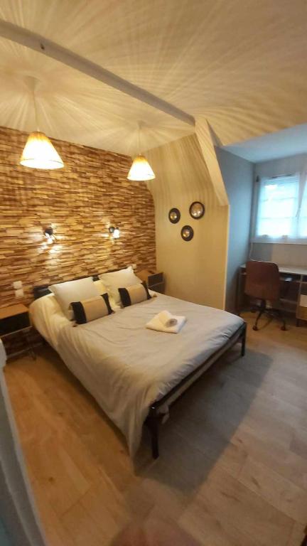 une chambre avec un grand lit et un mur de briques dans l'établissement La Renaissance, à Condé-sur-Noireau