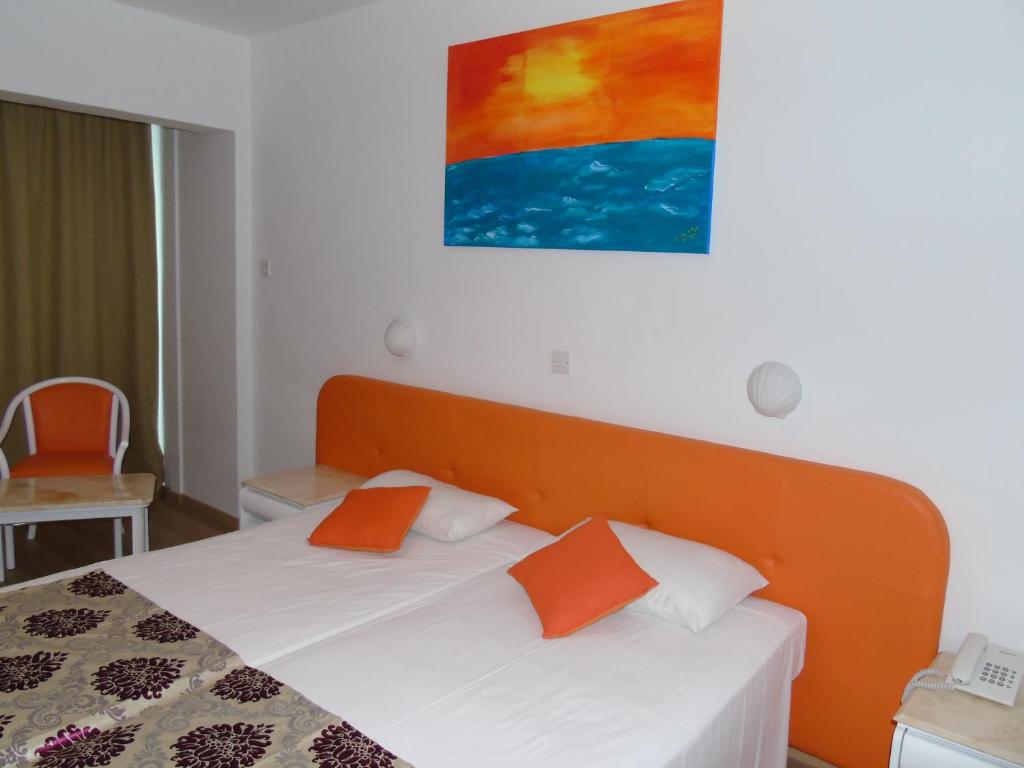 a bedroom with a bed with orange and white pillows at Corfu Hotel in Ayia Napa