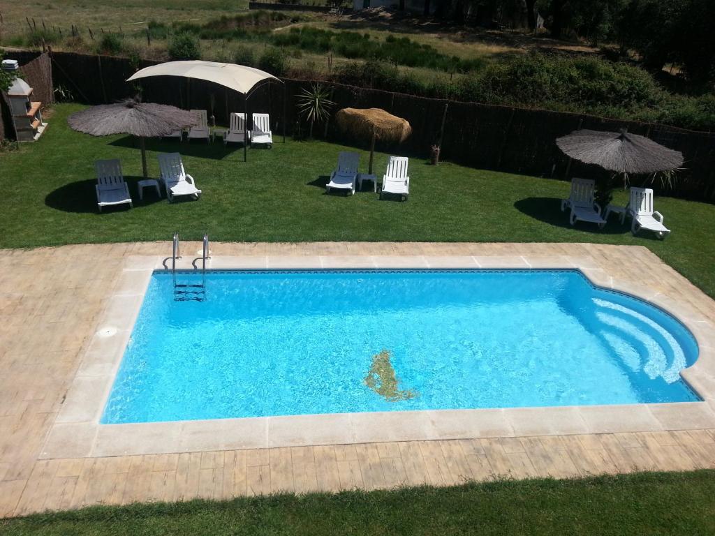 La Codosera的住宿－Casa Rural Sierra San Mamede，享有带椅子和遮阳伞的游泳池的上方景色
