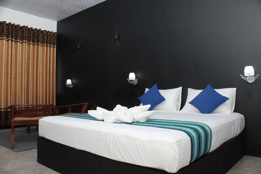 a bedroom with a large bed with blue and white pillows at Green Lake View Yala Resort in Tissamaharama