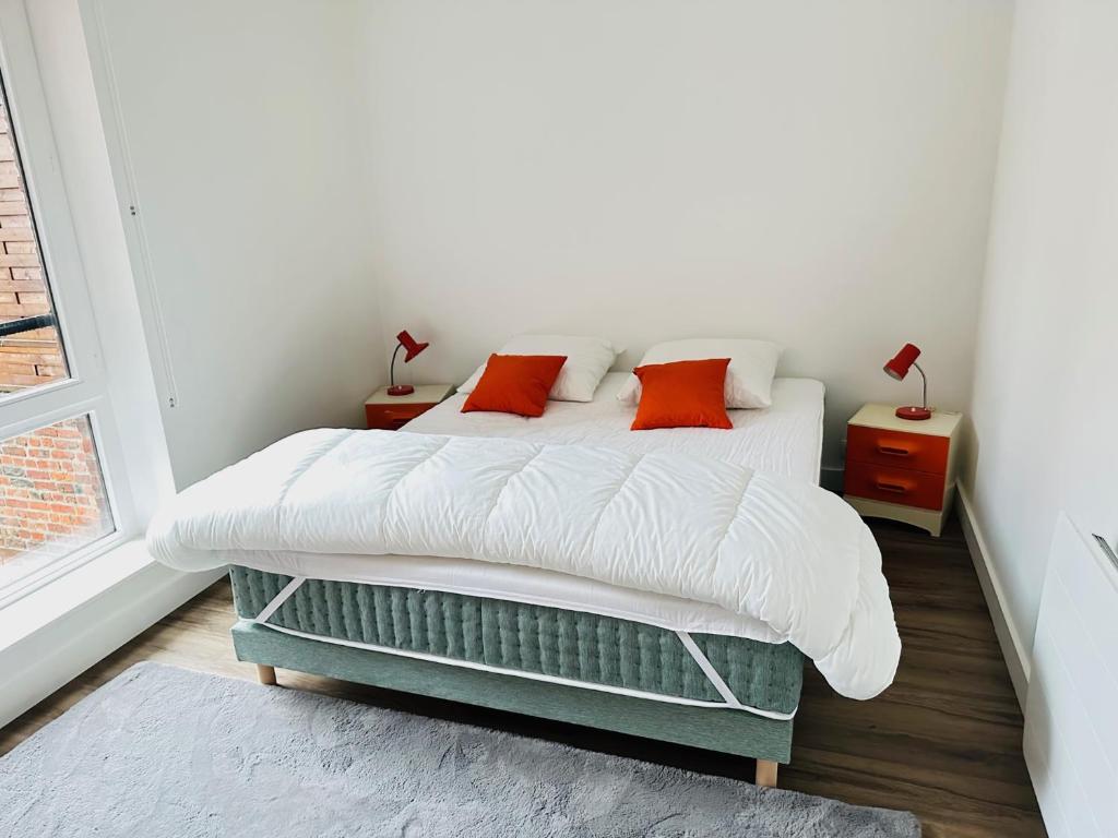 a bedroom with a bed with white and orange pillows at ORANGE APPART in Tourcoing