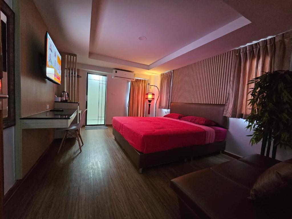 een slaapkamer met een rood bed en een bureau bij โรงแรมเซเว่นรัชดา S7VEN RATCHADA in Ban Na Song