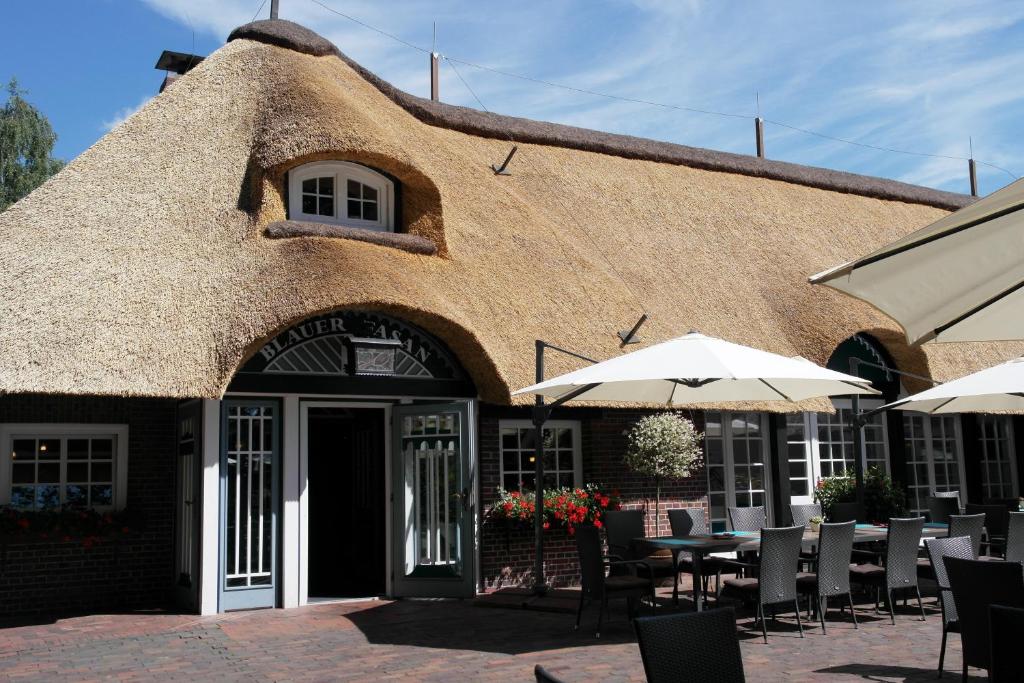 un restaurante con mesas y sombrillas frente a un edificio en Hotel Blauer Fasan, en Wiesmoor