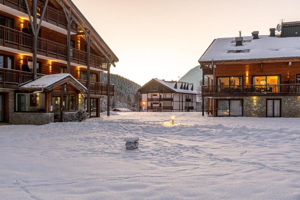 a dog sitting in the snow in front of buildings at Oasis Les Portes du Soleil Mountain Resort in La Chapelle-dʼAbondance