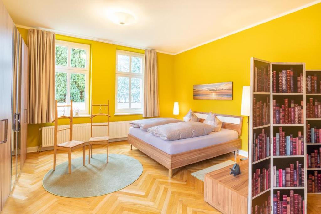 um quarto com paredes amarelas e uma cama e livros em Großzügige Fewo mit Terrasse, Strandkorb em Bansin