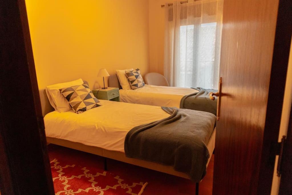1 dormitorio con 2 camas y ventana en Casa Angulosa, en Covilhã