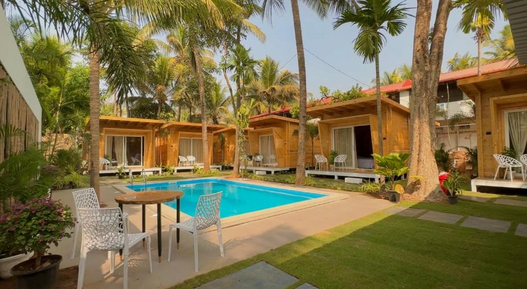 a villa with a swimming pool and palm trees at The Nine Beach Resort in Canacona
